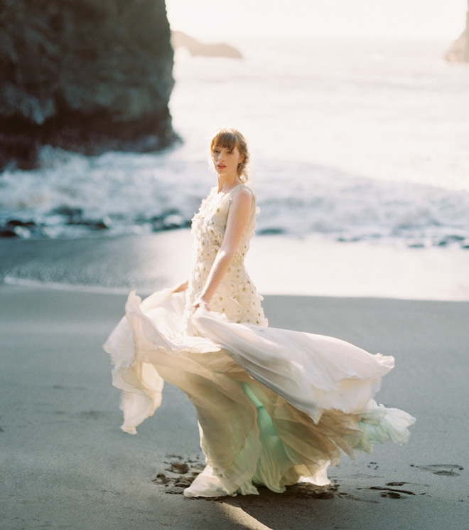 The bride standing in the sand with the Oregon Coast behind her.