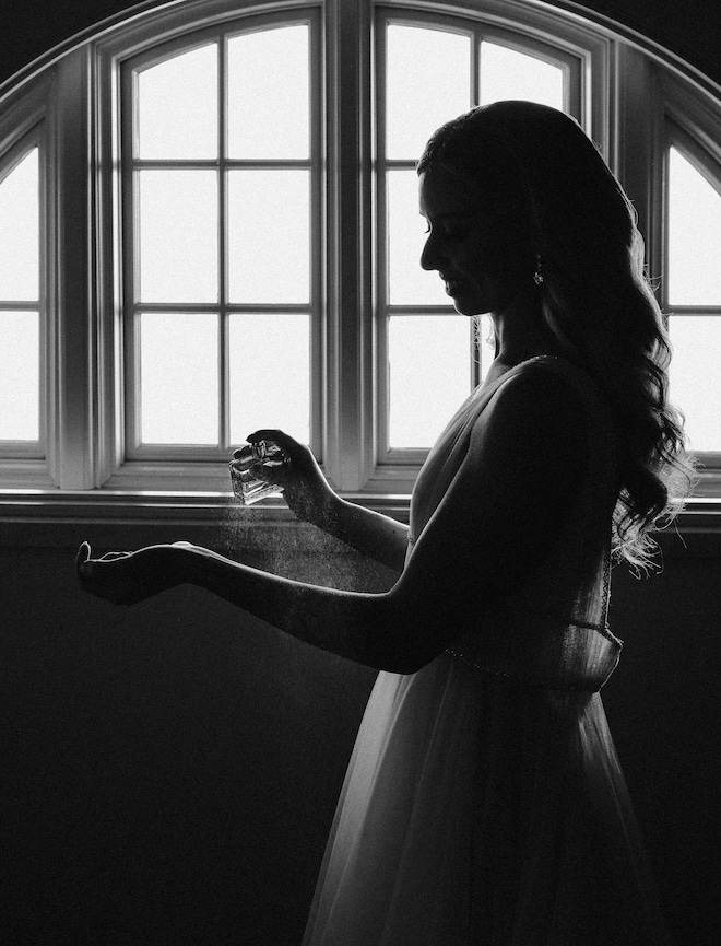 The bride spraying perfume on her wrist.