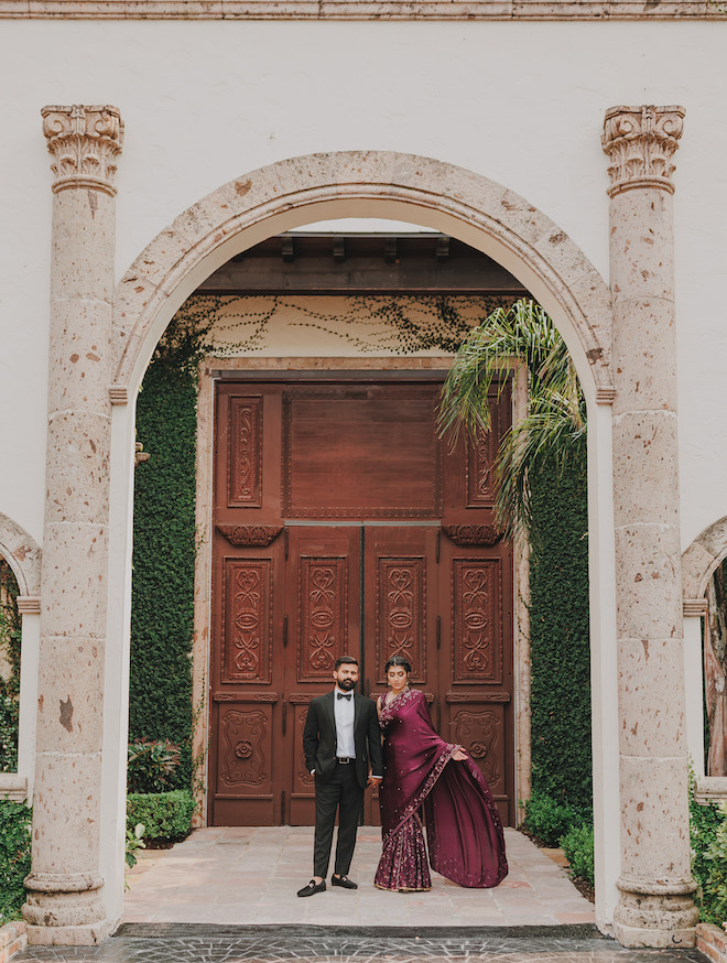 The bride and groom standing in front of a grand door.