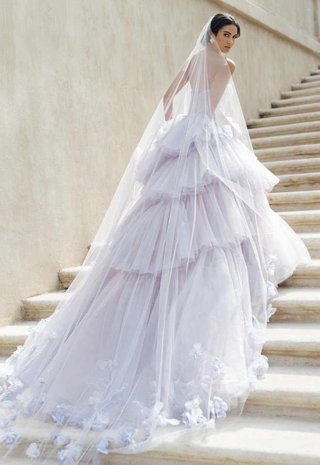 Bride walking up the stairs in a purple ruffle wedding gown with a purple veil.