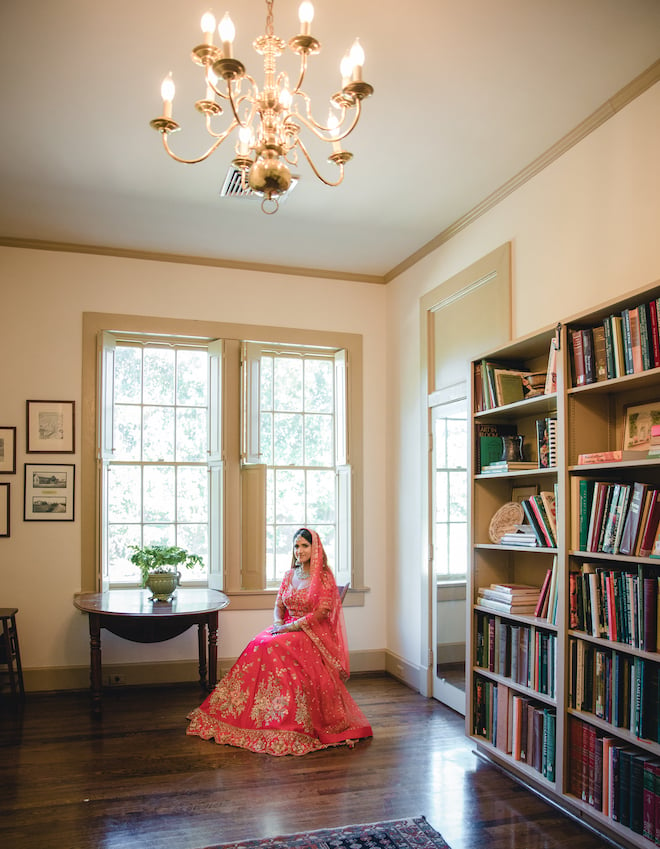 The bride sitting in a chair next to a window in her Nikkah outfit.