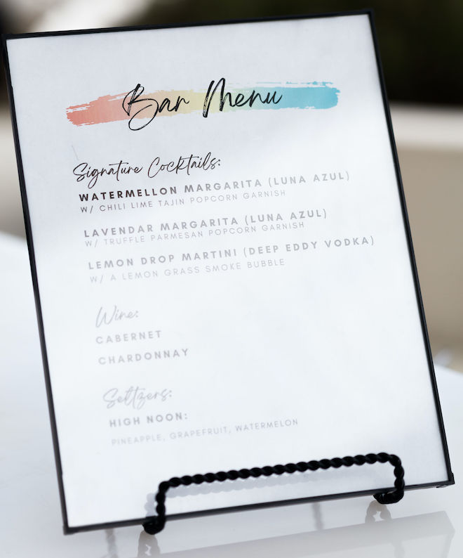 A framed bar menu with signature cocktails, wine and seltzers.