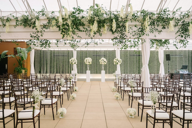 An open air veranda decorated for a ceremony with white florals and greenery.