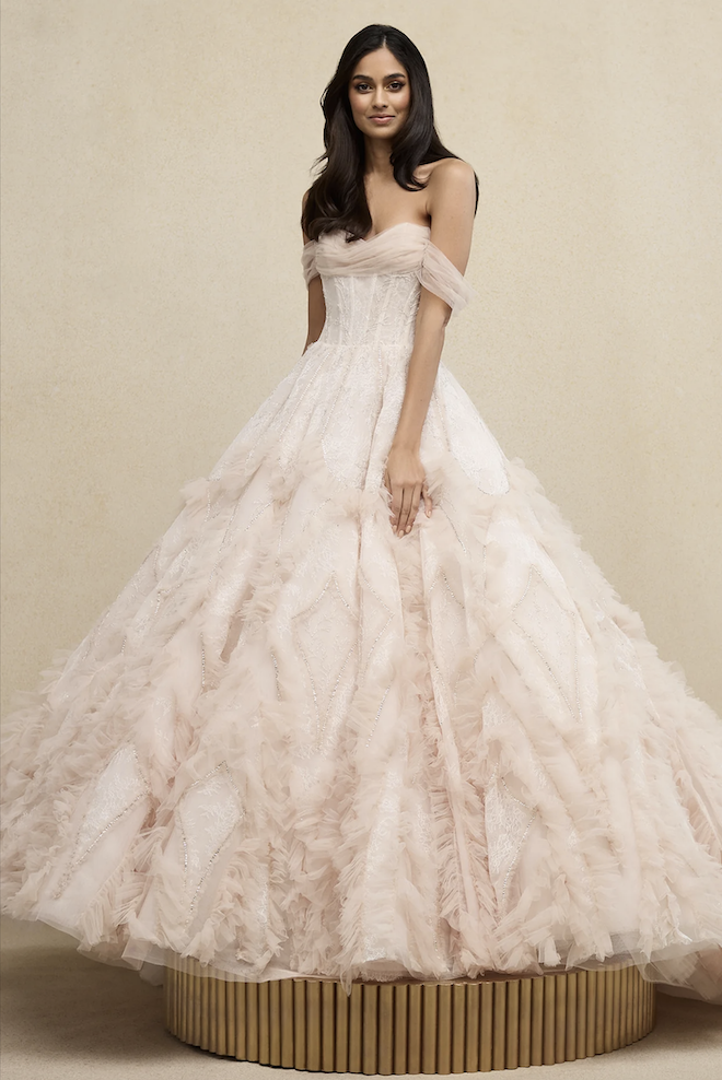 Model wearing an off the shoulder Cinderella ball gown with full textured skirt by Ines Di Santo.