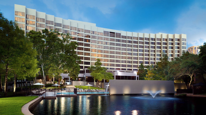 The exterior of the Omni Houston Hotel showcasing a pond and the pool.