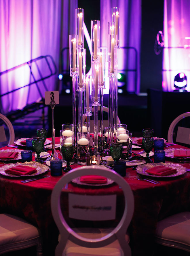 A round table decorated with red linens and pillar candles.