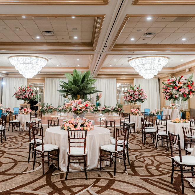 A ballroom with two crystal chandeliers decorated for a wedding reception at the hotel wedding venue, The San Luis Resort, Spa and Conference Center in Galveston, TX.