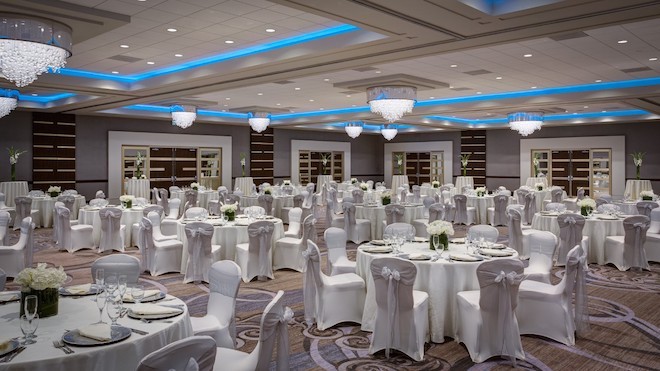 The grand ballroom decorated with white tables and white chairs.