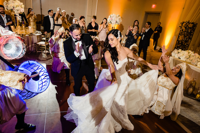The bride and groom dancing at the reception with performers surrounding them. 