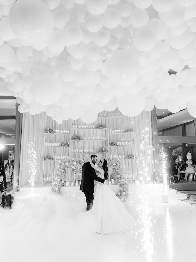 Bride and groom have their first dance on a fog covered dance floor surrounded by cold sparklers at a wedding reception at Omni Houston Hotel. 