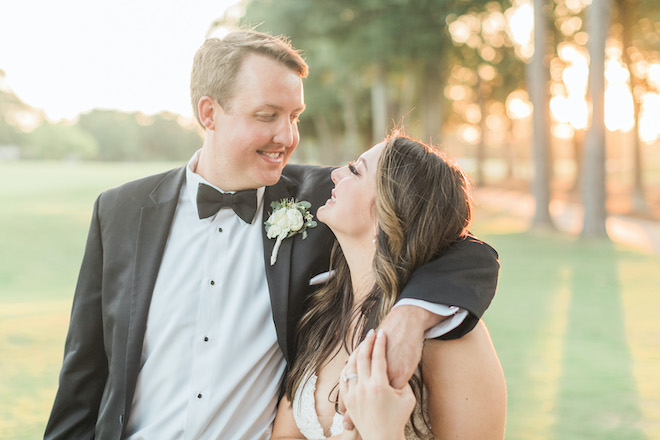 The groom having his arm around the bride while smiling at each other. 