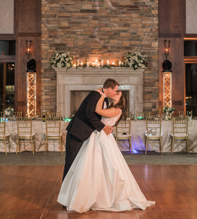 The bride and groom kissing on the dance floor with white sage and blush decor.