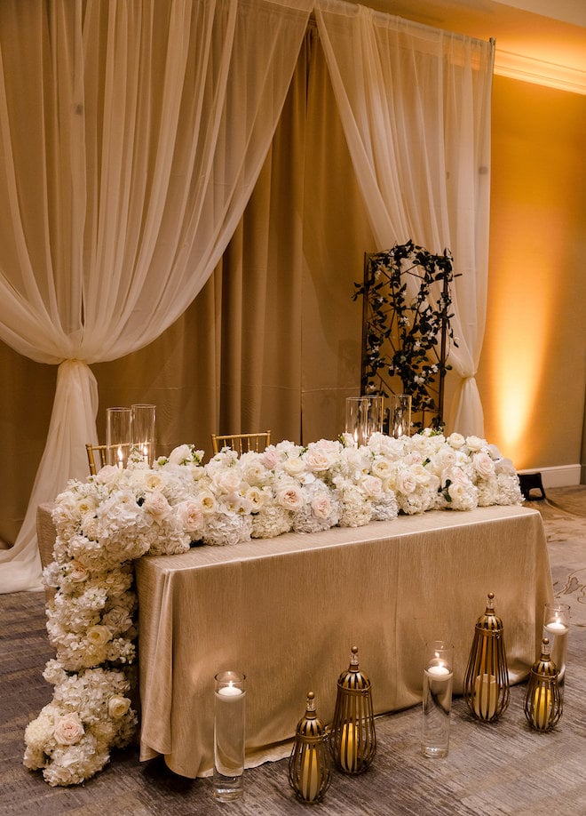 The head table covered in white and blush florals. 