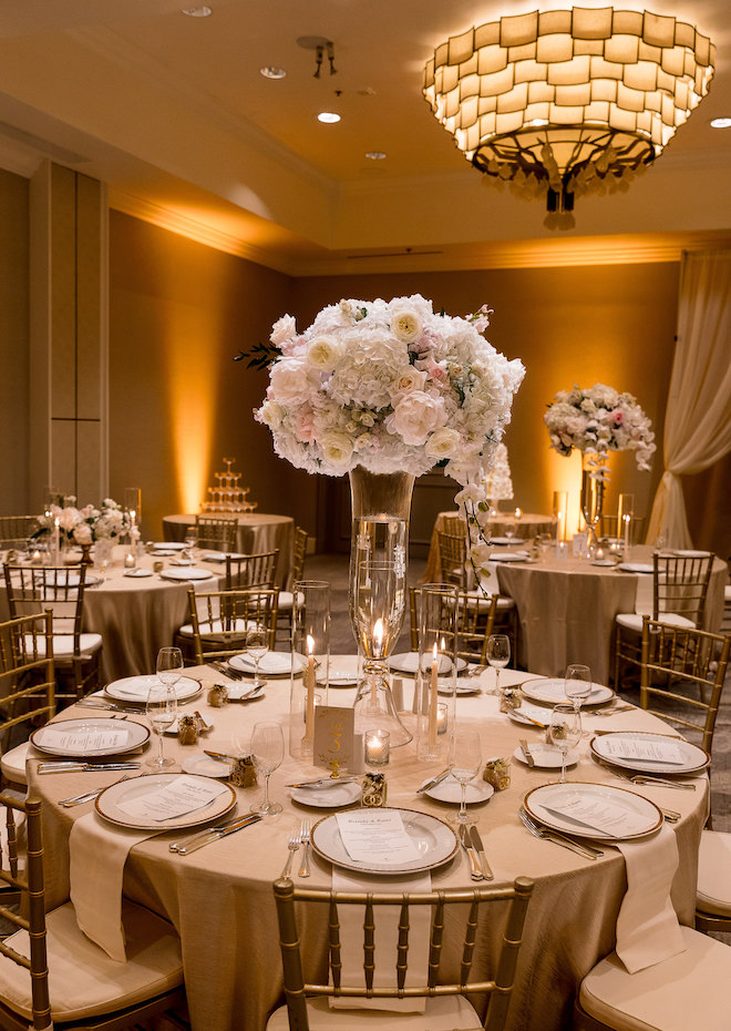 A round dining table with white and pink floral centerpieces.