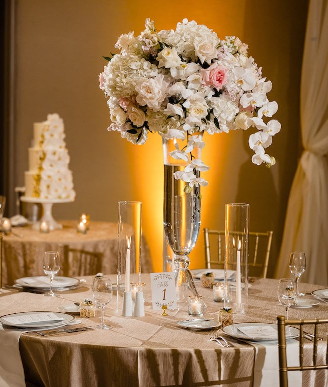 A white and pink floral centerpiece on a round dining table.