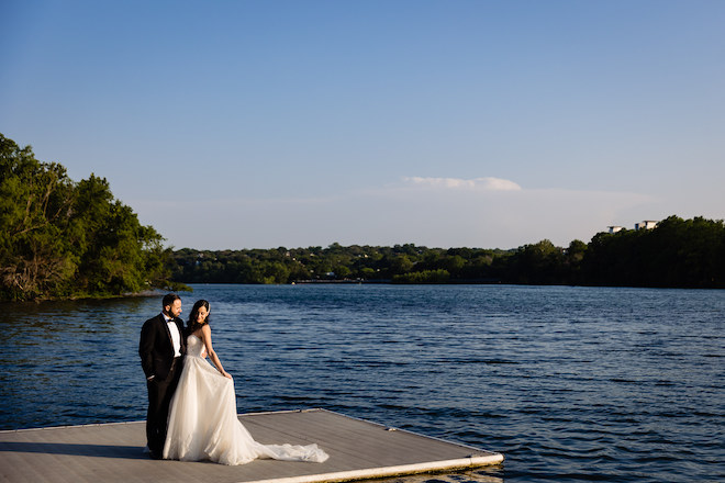 The bride and groom posing on a boardwalk on Lady Bird Lake in Austin.