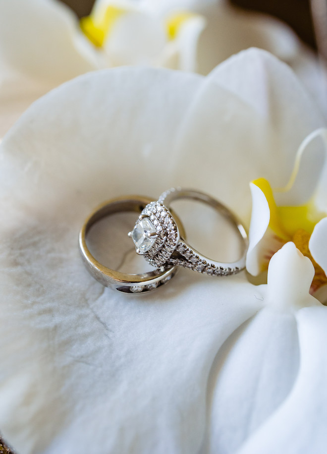 A diamond ring and band on a white flower. 