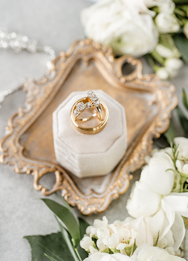 The diamond rings and gold band sitting on a ring box.