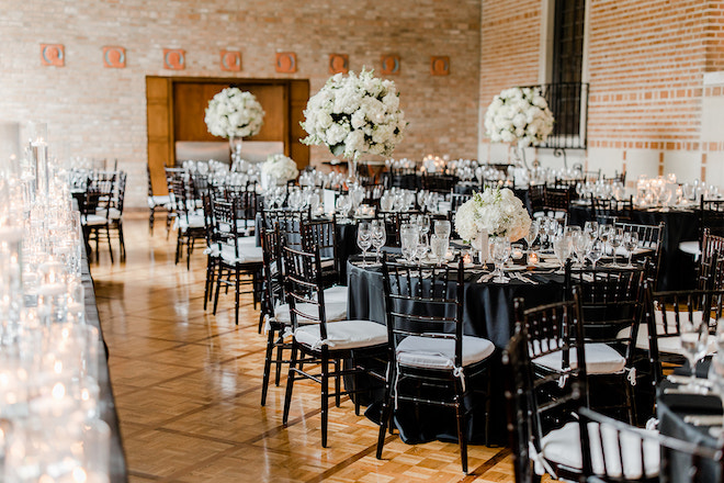 Black circular reception tables with white floral centerpieces and candlelight. 