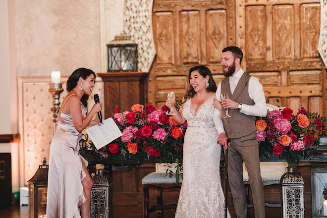 The maid of honor singing her speech to the bride and groom. The bride and groom are holding champagne and smiling at the maid of honor. 