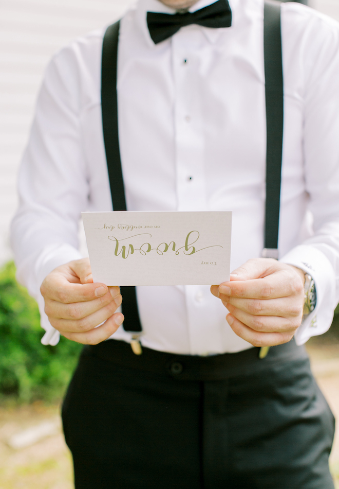 The groom holding a letter that says "To My Groom" in gold lettering.