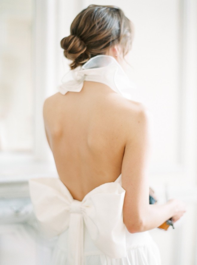 A bride wearing a wedding gown tied around her neck and a bow in the back.
