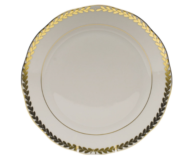 A white dinner plate from Herend with gold detailing on the edge of the plate. 