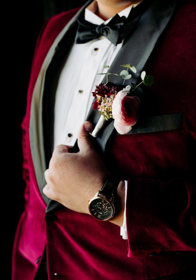 The groom's maroon suit with a white button up and black bow-tie. 