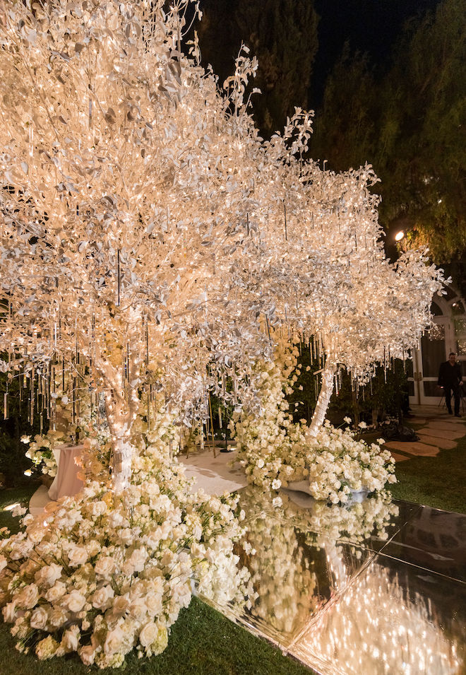 The altar decorated with white florals and icicle-inspired trees lit up with lights. 