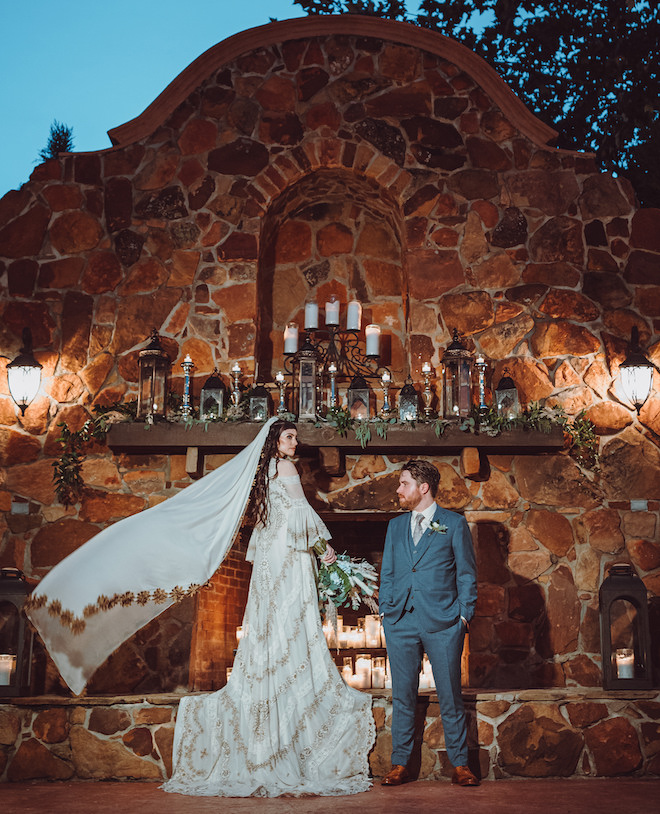 The bride standing on the altar at Madera Estates with her veil flowing while the groom looks at her.