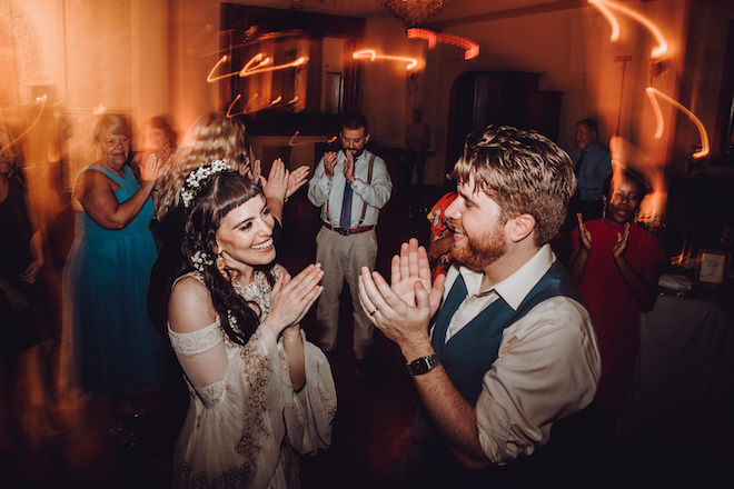 The bride and groom clapping on the dance floor at the reception.