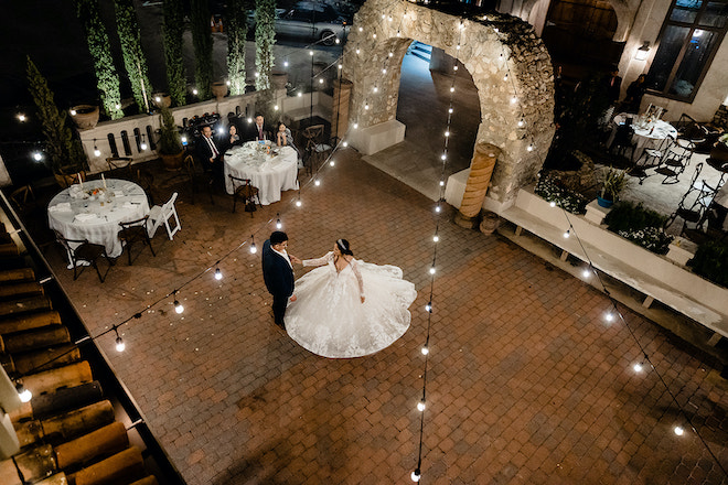 The bride and groom dancing under the twinkling lights. 
