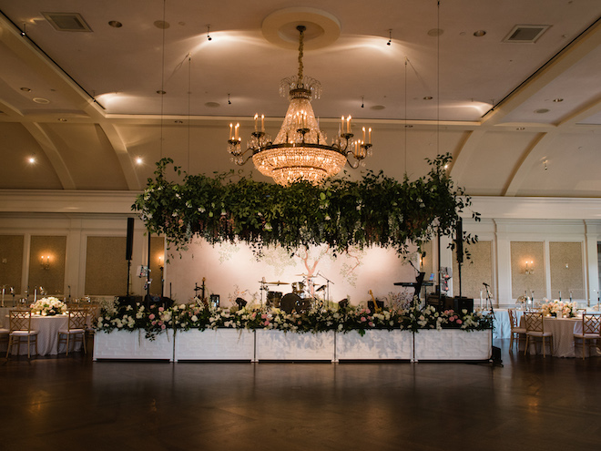The reception space with french garden inspired florals draping over the dance floor and in front of the stage. 