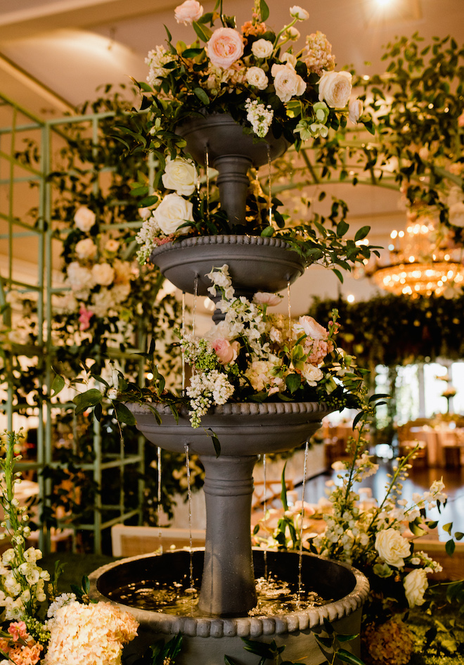 A three-tier working fountain with pink and white florals decorating the fountain for a french garden wedding in Houston. 