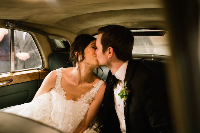 The bride and groom kissing in the getaway car. 