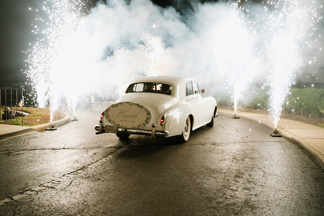 A 1965 Rolls Royce Princess with a "Just Married" sign and fireworks on either side of the car. 