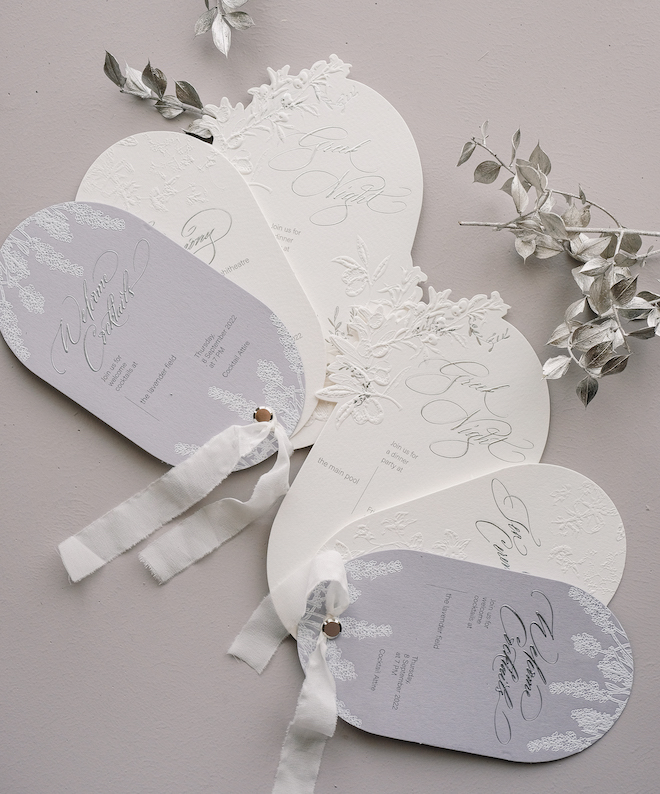 White and lavender oval invitations with calligraphy.