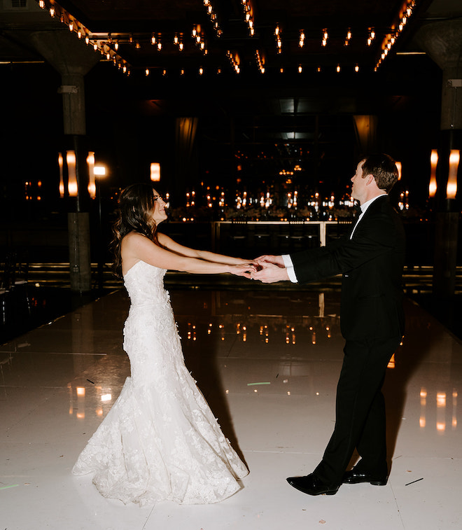 The bride and groom holding hands during their private last dance. 
