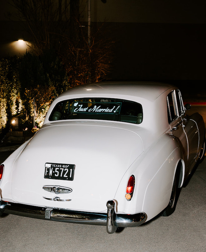 A white vintage getaway car with "Just Married!" written on the back windshield.