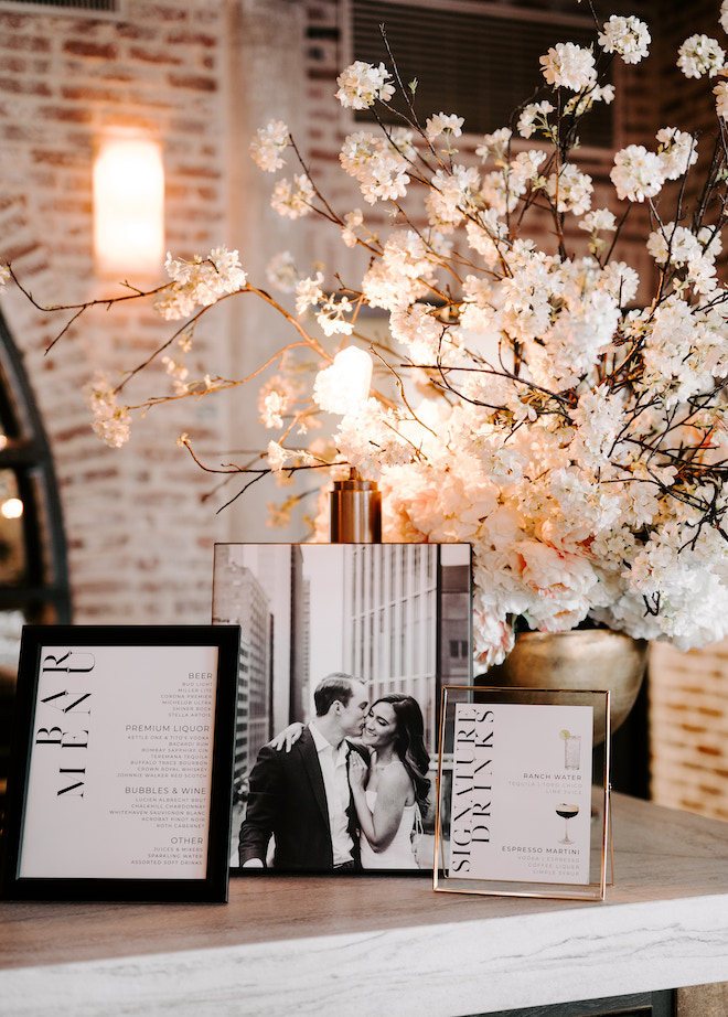 Three framed photos sitting on the edge of the bar. One of Haley and Craig, one of the signature drinks and the other of the bar menu. 