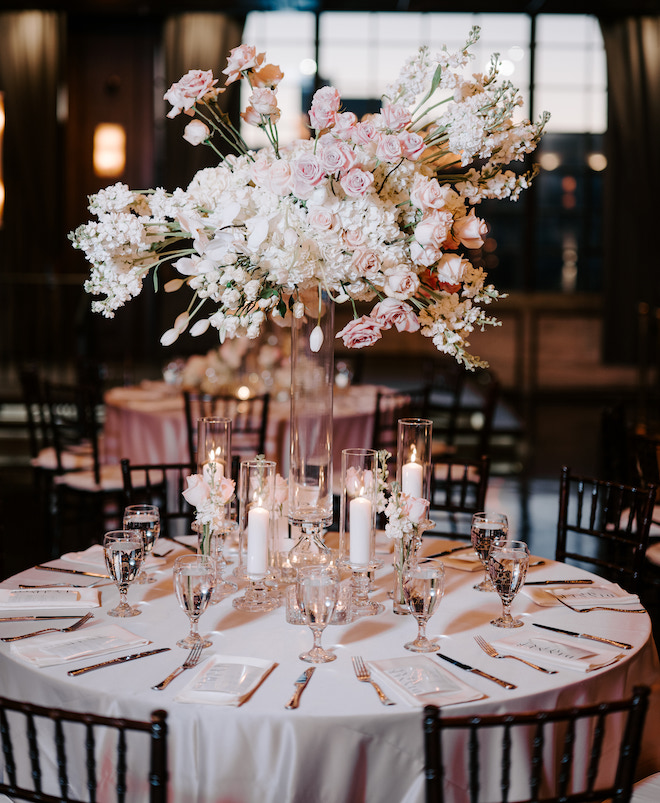 A round reception table with a tall floral arrangement of white and blush florals. 