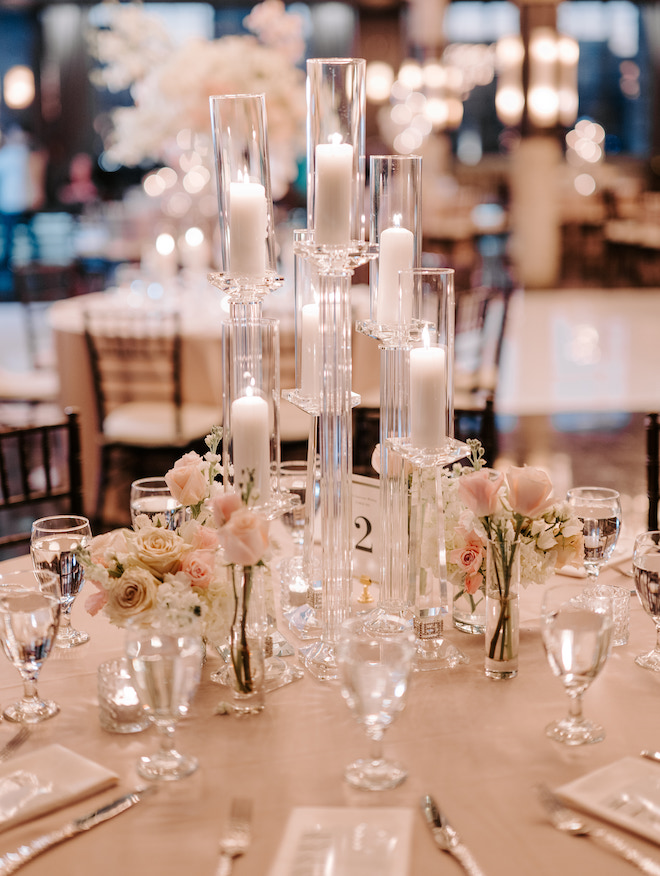 A round reception table with tall candles and white and blush florals. 