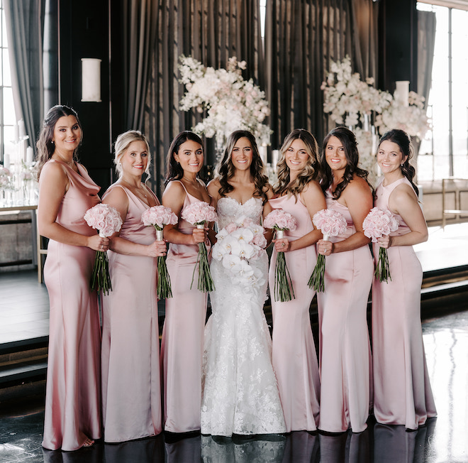 The bride and bridesmaids posing in blush pink gowns with blush bouquets. 