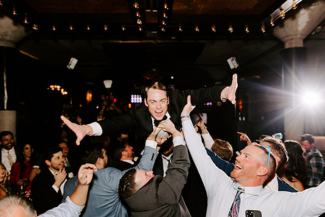 The groom crowd surfing at the reception. 