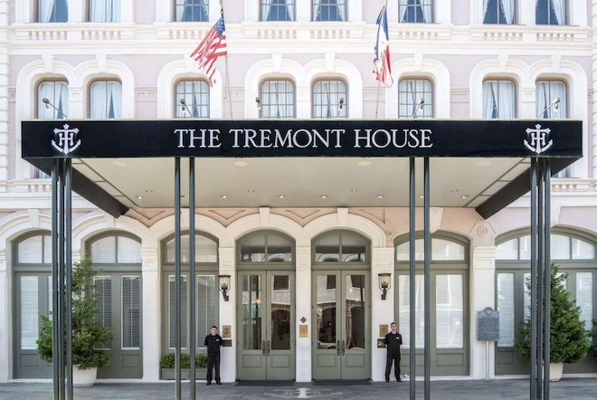 The front of The Tremont House with two men standing next to the green doors below the "The Tremont House" sign.