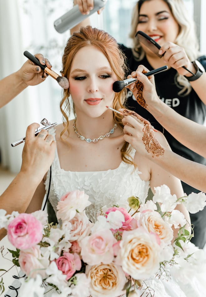 A bride in a precious jewel necklace from tenenbaum jewelers has makeup and hair products applied by Polished Makeup and Hair at wedding venue, The Laura Hotel in Houston, TX.