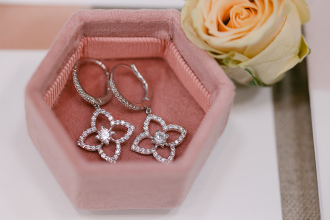 A pink velvet jewelry box with dangly diamond earrings.