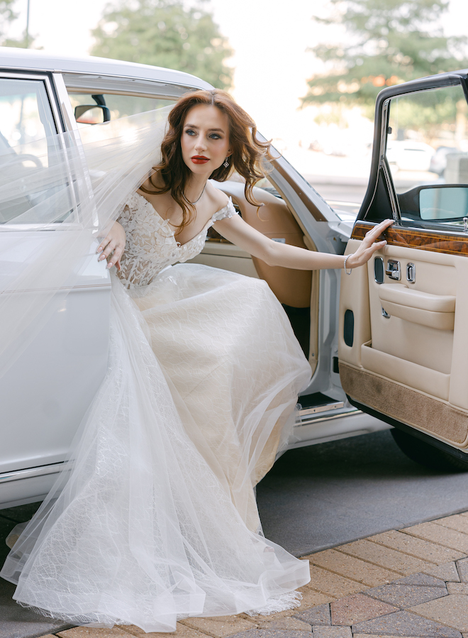 The bride sitting in the vintage Rolls Royce with the door open and her veil flowing out.