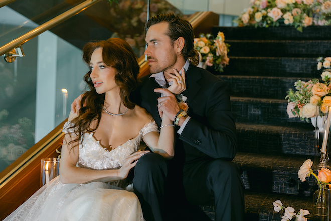 The bride and groom looking to the side while sitting on the staircase at The Westin Houston Memorial City.