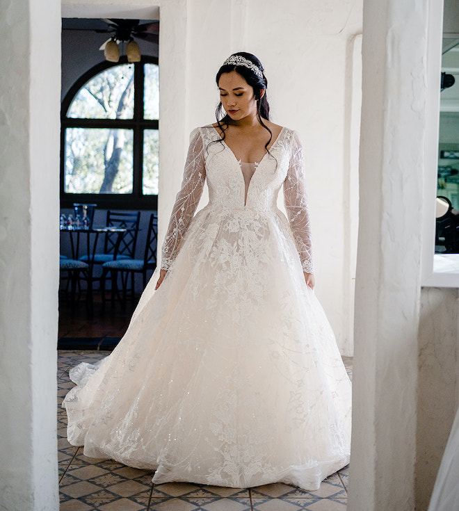 A bride wearing a long sleeve lace dress with a sparkly head piece. 